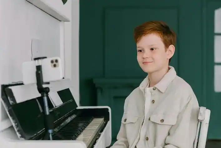 A young male student on a video call with his parents to show them his piano recital