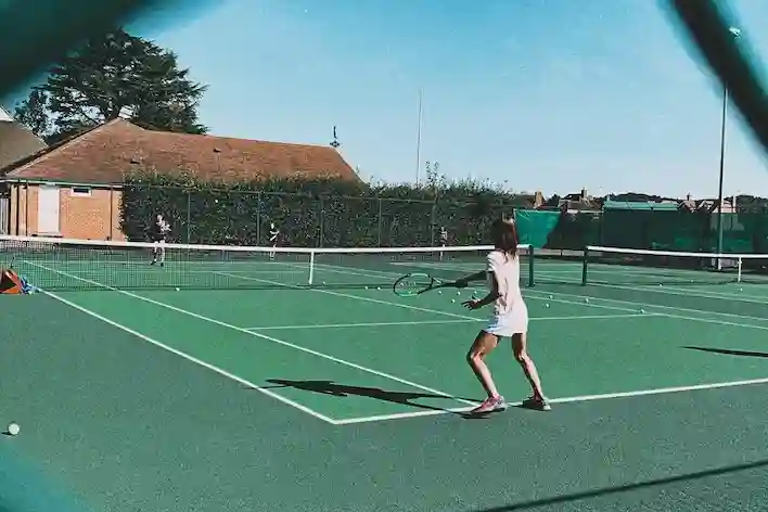 A photograph of teenage students playing tennis.
